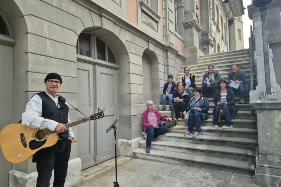 Maibummel: ein Sänger mit Gitarre spielt für die Mitglieder auf einer Freitreppe